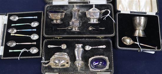 A set of six enamelled silver coffee spoons, an egg cup and spoon Christening set and two condiment sets, all cased